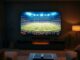 Televize v obývacím pokoji se sportovním přenosem z fotbalového stadionu