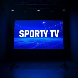 Televizní obrazovka s nápisem Sporty TV v setmělém studiu