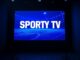 Televizní obrazovka s nápisem Sporty TV v setmělém studiu