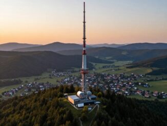 Televizní vysílač na zalesněném hřebeni nad vesnicí při východu slunce